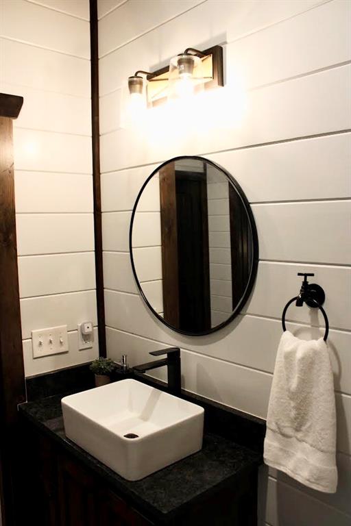 bathroom featuring wooden walls and vanity