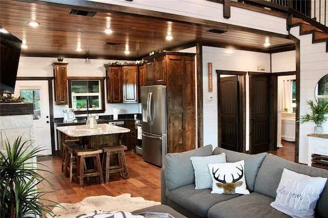 kitchen with dark brown cabinetry, stainless steel fridge with ice dispenser, hardwood / wood-style floors, a kitchen island, and wood ceiling