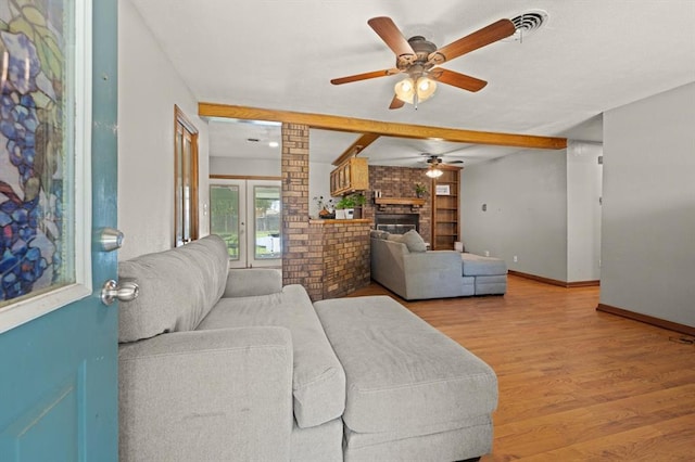 living room with french doors, brick wall, ceiling fan, light hardwood / wood-style flooring, and a fireplace