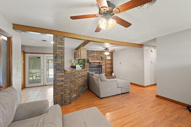 living room with a brick fireplace, ceiling fan, vaulted ceiling with beams, and light hardwood / wood-style flooring