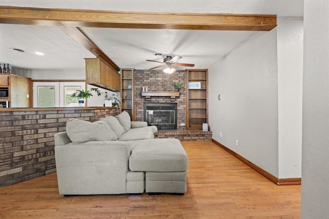 living room featuring a brick fireplace, light hardwood / wood-style flooring, and beam ceiling