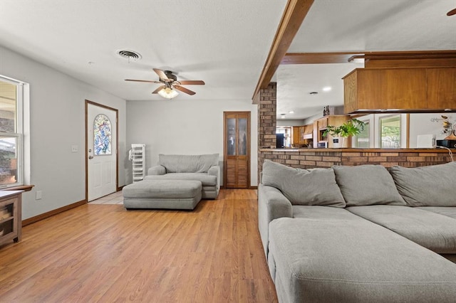 living room featuring ceiling fan, beamed ceiling, and light wood-type flooring