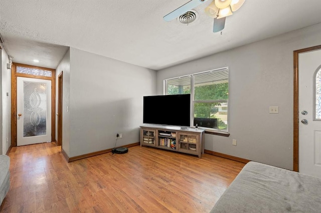 living room with a textured ceiling, light hardwood / wood-style flooring, and ceiling fan