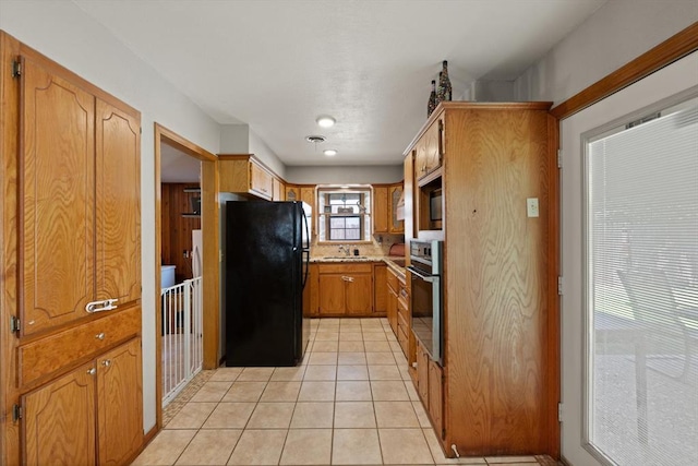 kitchen with black appliances, light tile patterned floors, and sink