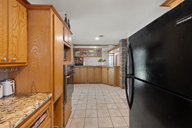 kitchen with black appliances, light stone counters, and light tile patterned floors