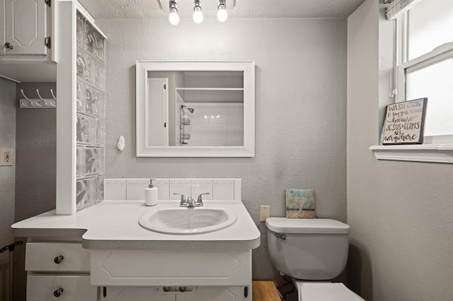 bathroom with a shower, a textured ceiling, vanity, and toilet