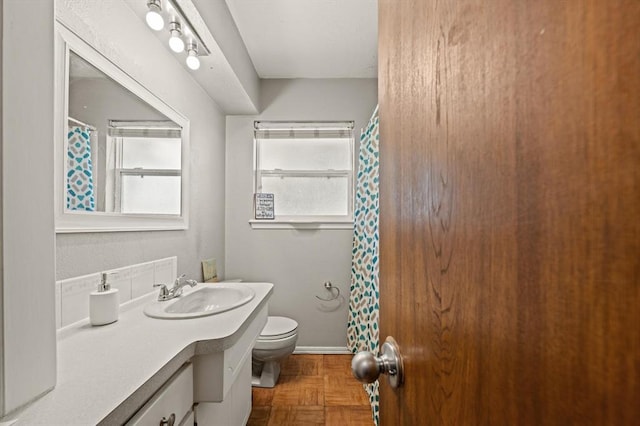 bathroom featuring vanity, toilet, and parquet flooring