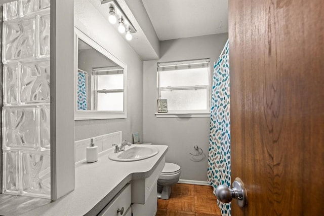 bathroom featuring parquet flooring, vanity, and toilet