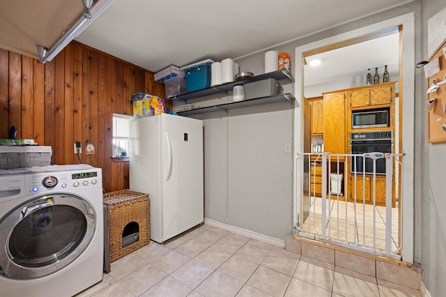 laundry room featuring light tile patterned flooring, washer / dryer, and wooden walls