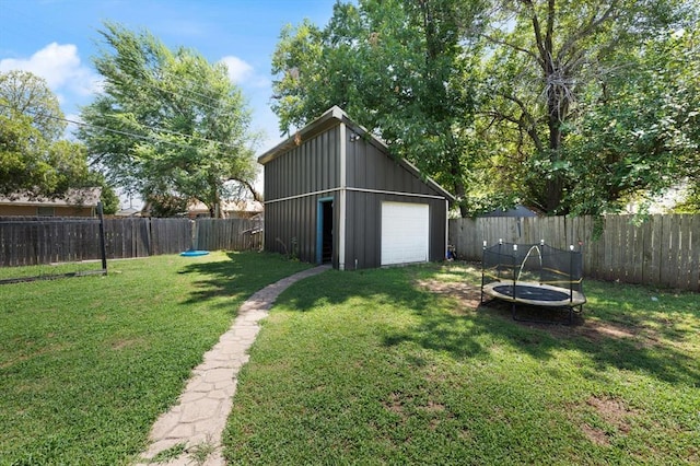 view of yard with a garage, an outdoor structure, and a trampoline