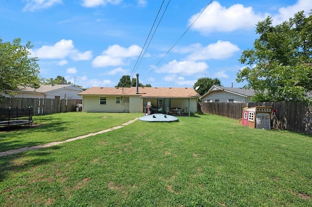 back of house featuring a yard and a trampoline