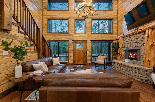 living room featuring a towering ceiling, a chandelier, a fireplace, and wooden walls