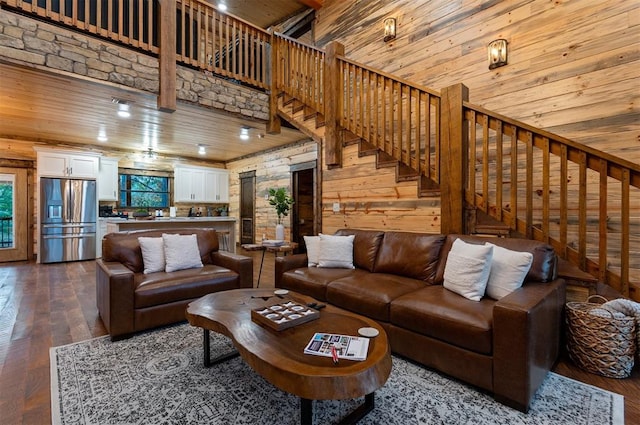 living room featuring hardwood / wood-style floors, wood ceiling, wooden walls, and a towering ceiling