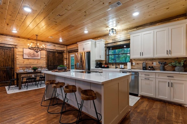 kitchen featuring appliances with stainless steel finishes, white cabinetry, a kitchen breakfast bar, a kitchen island, and decorative light fixtures