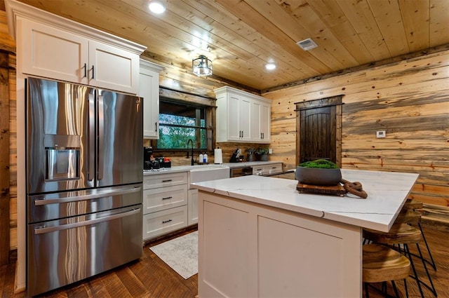 kitchen featuring wood ceiling, white cabinetry, stainless steel refrigerator with ice dispenser, light stone countertops, and a kitchen island