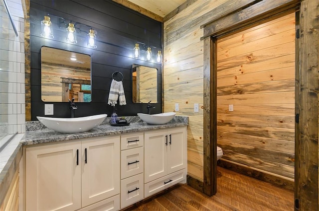 bathroom featuring vanity, wood-type flooring, toilet, and wood walls