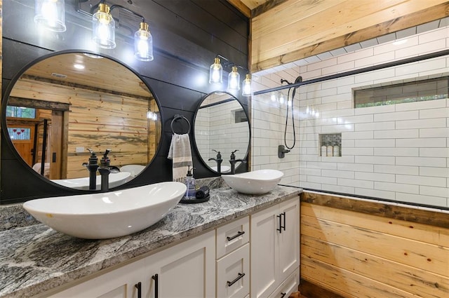 bathroom with vanity, a tile shower, and wooden walls