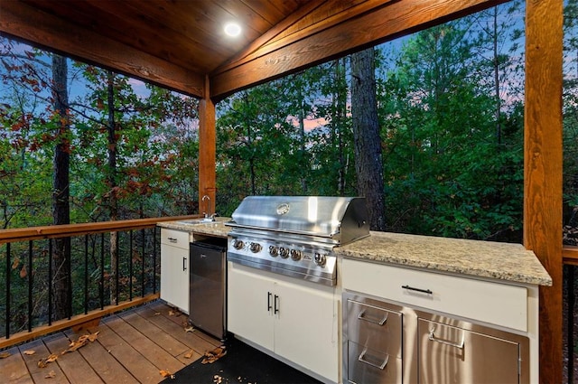 exterior space featuring an outdoor kitchen, a grill, a deck, and sink