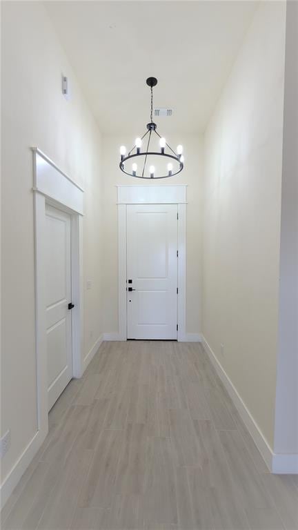 doorway with light hardwood / wood-style flooring and a notable chandelier