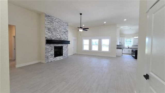 108 Tralee Ct, Yukon, OK 73099 - unfurnished living room featuring ceiling fan, plenty of natural light, a stone fireplace, light wood finished floors, and recessed lighting