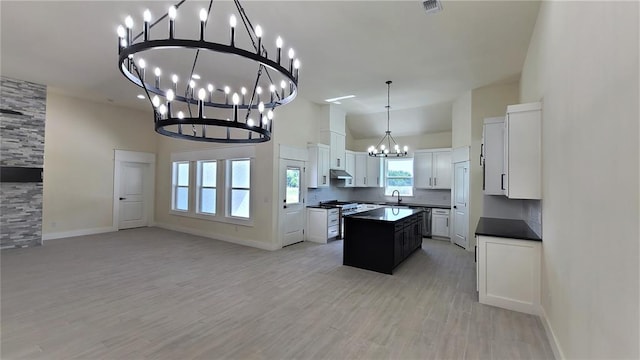 kitchen with a center island, stainless steel gas range oven, sink, light hardwood / wood-style floors, and white cabinetry