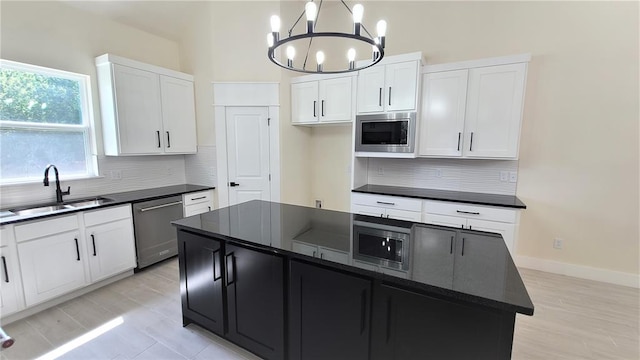 kitchen featuring sink, decorative light fixtures, a notable chandelier, a kitchen island, and stainless steel appliances