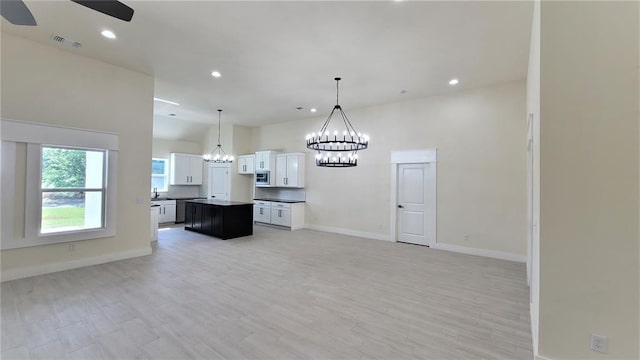 108 Tralee Ct, Yukon, OK 73099 - kitchen featuring open floor plan, a chandelier, stainless steel microwave, a ceiling fan, and white cabinets
