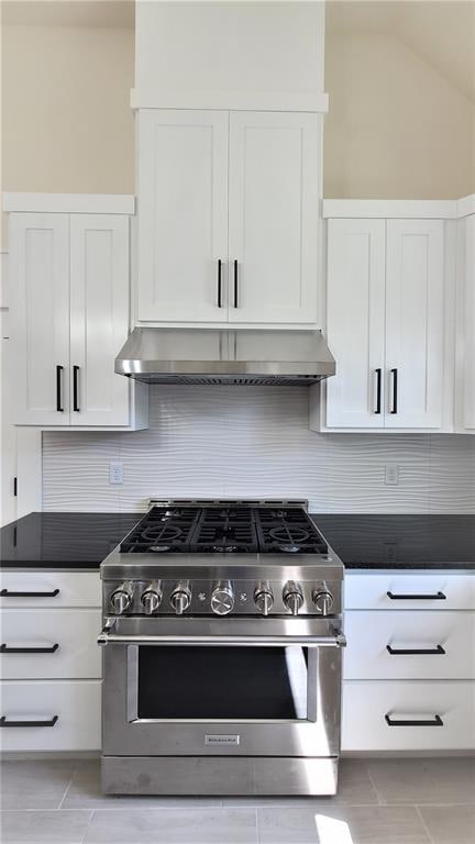 kitchen with white cabinets, backsplash, high end stainless steel range, and vaulted ceiling