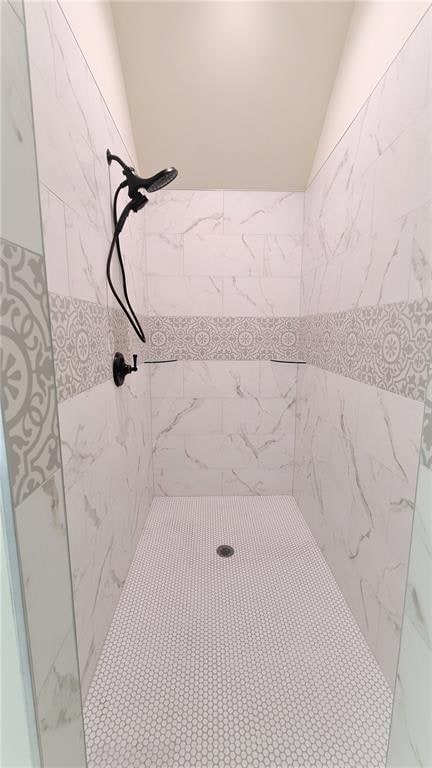 bathroom with vaulted ceiling and tiled shower