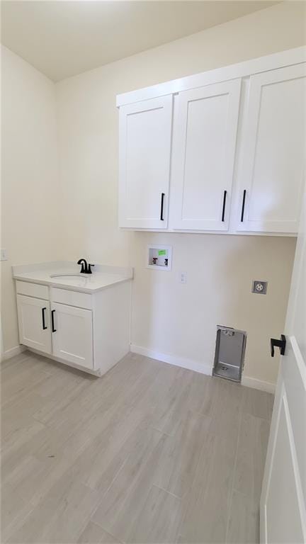 laundry area featuring cabinets, hookup for a washing machine, hookup for an electric dryer, sink, and light hardwood / wood-style floors