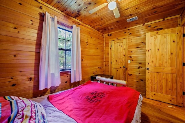 bedroom with wood ceiling, ceiling fan, and wood walls