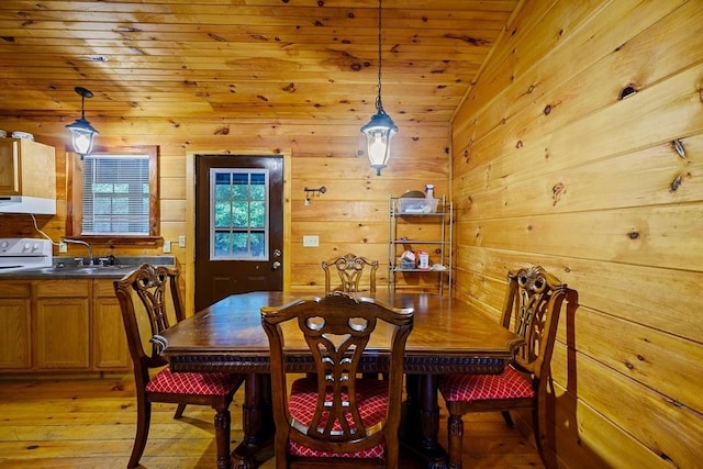 dining space with wood walls, wooden ceiling, sink, light hardwood / wood-style flooring, and vaulted ceiling