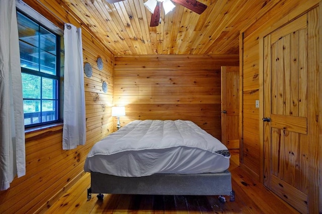 bedroom featuring wooden walls, ceiling fan, and hardwood / wood-style flooring