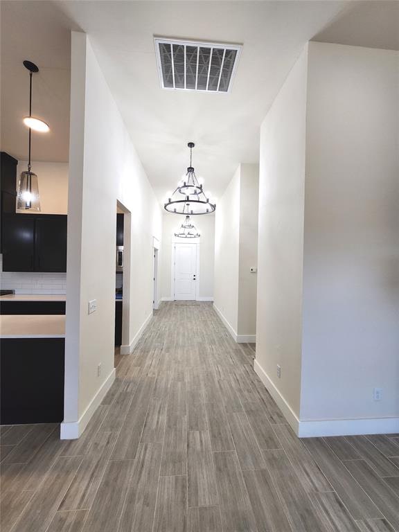 hallway featuring hardwood / wood-style floors and an inviting chandelier