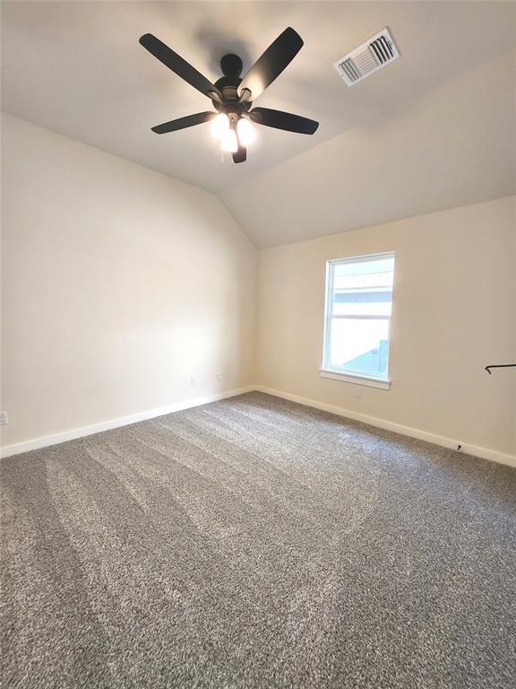 carpeted spare room with ceiling fan and lofted ceiling