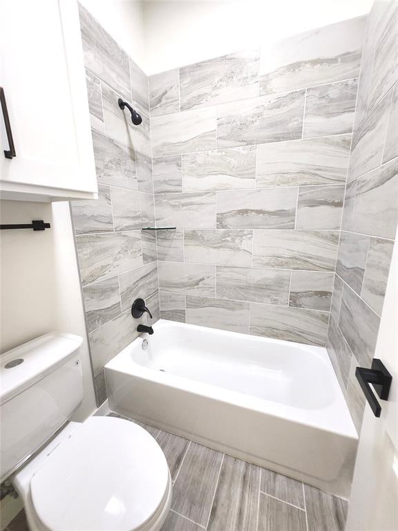 bathroom with tiled shower / bath combo and toilet