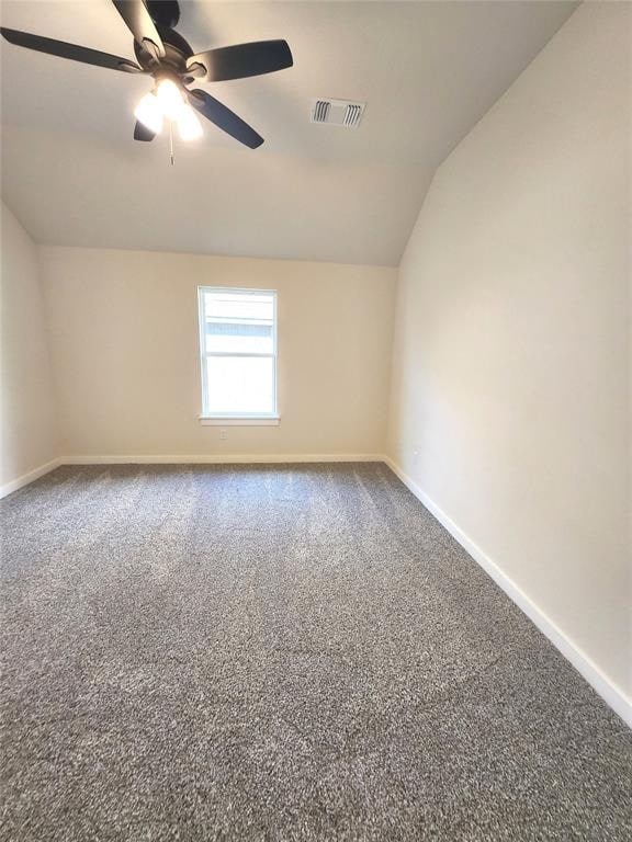 spare room featuring ceiling fan, carpet floors, and vaulted ceiling