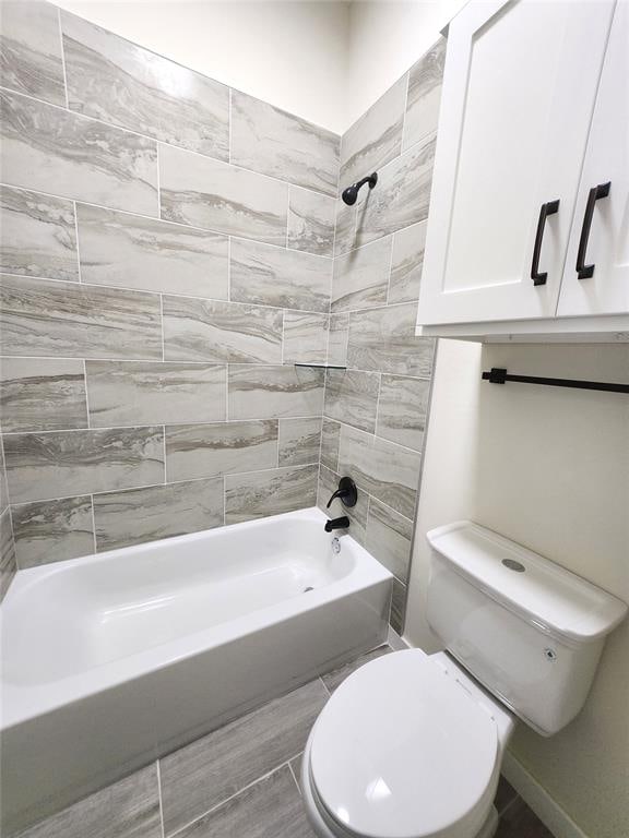 bathroom with tiled shower / bath combo and toilet