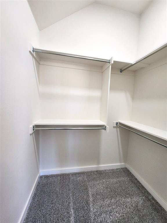 spacious closet with dark carpet and lofted ceiling