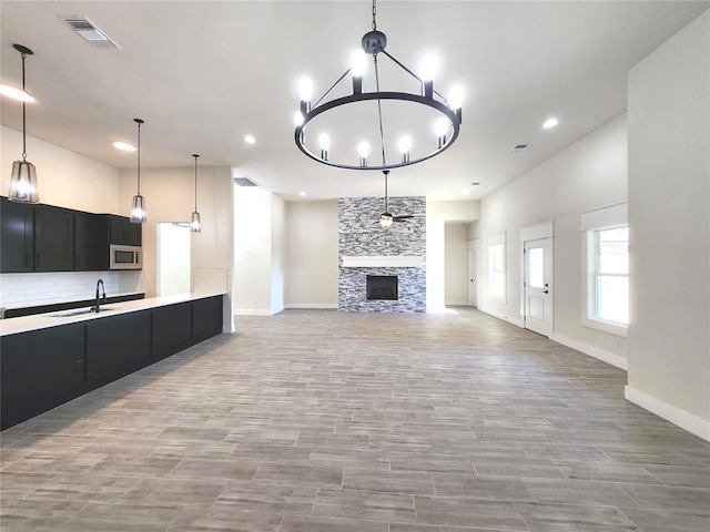 unfurnished living room with a fireplace, sink, and a chandelier