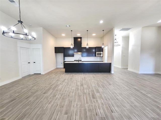 kitchen featuring a center island with sink, an inviting chandelier, light hardwood / wood-style floors, and sink