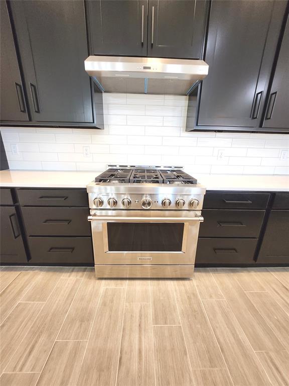 kitchen featuring backsplash, high end stainless steel range oven, and light hardwood / wood-style flooring