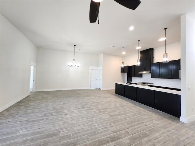 kitchen with light wood-type flooring, a center island, ceiling fan with notable chandelier, and decorative light fixtures