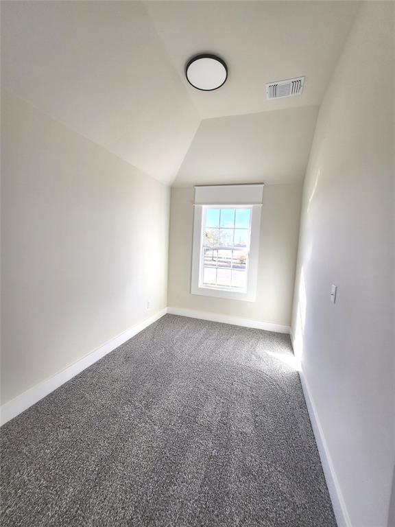 carpeted empty room featuring lofted ceiling