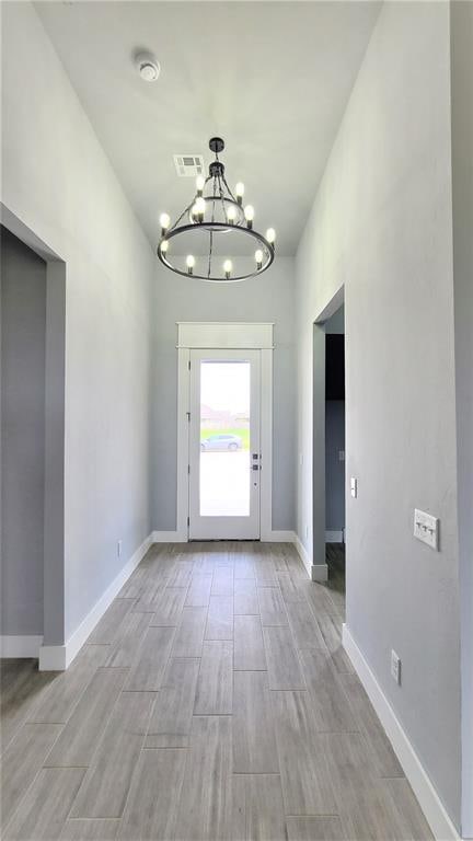 entryway with light hardwood / wood-style flooring and an inviting chandelier