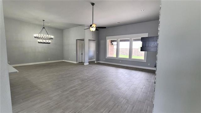 unfurnished living room with ceiling fan with notable chandelier and wood-type flooring