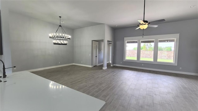 interior space with ceiling fan with notable chandelier and hardwood / wood-style flooring