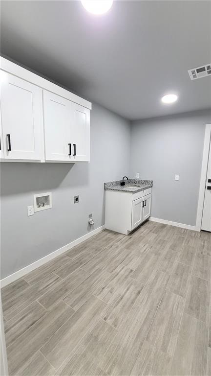 clothes washing area with cabinets, sink, light hardwood / wood-style flooring, washer hookup, and hookup for an electric dryer