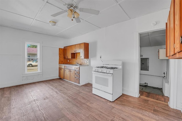 kitchen featuring backsplash, electric panel, ceiling fan, light hardwood / wood-style floors, and white range with gas cooktop