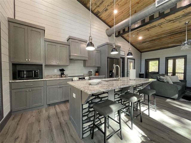 kitchen with sink, stainless steel appliances, hanging light fixtures, high vaulted ceiling, and a kitchen bar